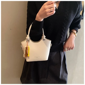 Détail du sac seau en cuir PU blanc avec texture litchi et breloque en perles