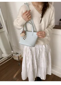 Detail of light blue bucket bag with fluffy dog charm and stylish beaded accessory