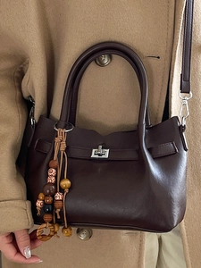 Brown leather handbag with silver twist lock and ethnic beaded tassel on khaki coat
