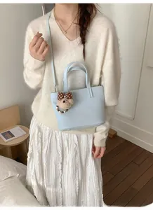 Fashion light blue lychee pattern leather bucket bag with cute plush bear charm on model