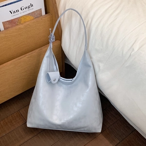 Dettaglio della borsa hobo azzurra con texture raffinata e logo del marchio in argento