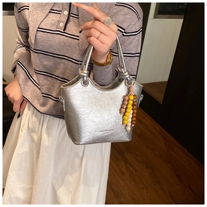 Détail du sac seau métallisé argenté avec texture plissée et breloque en perles colorées