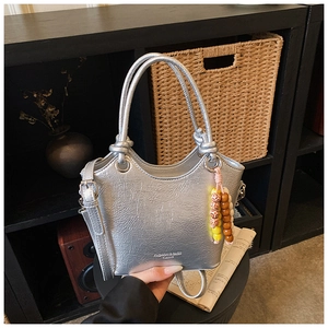 Détail du sac seau métallisé argenté avec texture plissée et breloque en perles colorées