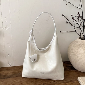 Dettaglio di una borsa hobo vintage bianca su un tavolo di legno con tracolla a nodi
