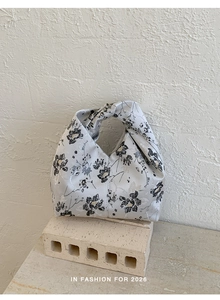 Detailansicht der geblümten Jacquard-Knotentasche mit edlem Stoff auf einem Steinsockel