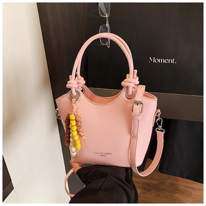Détail du sac seau rose avec texture plissée, doubles poignées et pompon de perles colorées