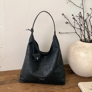 Dettaglio della borsa tote nera vintage con logo su un tavolo di legno rustico
