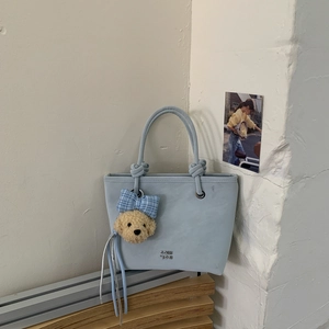 Close-up of light blue bucket bag with GOHH SON logo and cute teddy bear charm