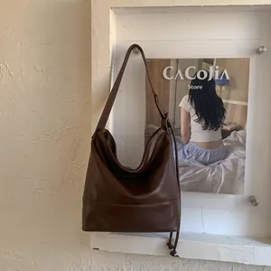 Macro detail of high-quality brown faux leather shoulder bag with side drawstring accents