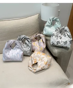 Schicke Blumen-Satin-Taschen in Pastellfarben, arrangiert auf einem beigen Sofa