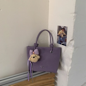 Close-up of a purple bucket bag with matte texture and a cute teddy bear charm