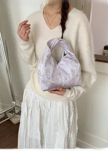 Detail der fliederfarbenen Satin-Cloud-Tasche mit Blumenmuster und Knotengriff
