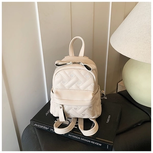 Nahaufnahme cremefarbener Mini-Rucksack mit Herzsteppung und Schleife auf Büchern