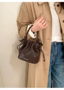 Detailed view of brown leather drawstring bucket bag with branded logo and fine texture