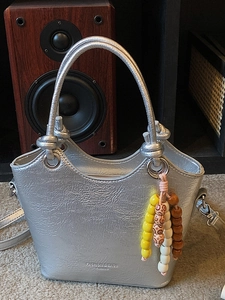 Sac seau argenté en cuir verni plissé avec poignée tressée et breloque en perles