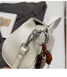 Détail du sac en cuir crème avec crochet en métal argenté et perles en bois décoratives