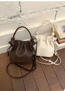Detail view of coffee and ivory pleated bucket bags with drawstrings and knot straps