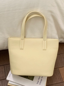 Minimalist beige leather tote bag with lychee texture on wooden floor background