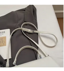 Détail de la bandoulière réglable en cuir blanc avec boucle argentée polie sur un sac