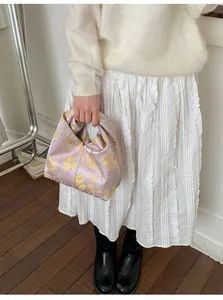 Detailansicht der fliederfarbenen Satin-Knotentasche mit gelbem Blumenmuster