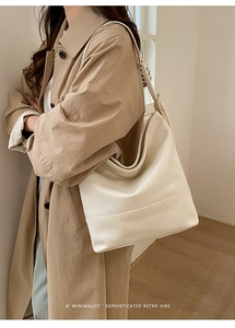 Detailed view of cream PU leather shoulder bag with stitching on khaki trench coat