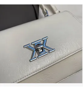 Détail du sac baguette blanc cassé avec fermoir rotatif en métal argenté en forme de XK