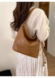 Sophisticated retro large brown leather tote bag worn by a model in a minimalist setting