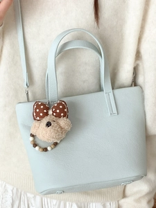 Light blue lychee texture handbag with cute bear charm worn as a crossbody shoulder bag