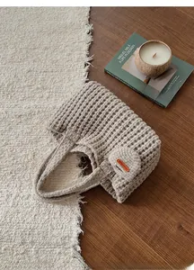 Détail d'un sac cabas en tricot crème fait main avec petit charm et étiquette en cuir