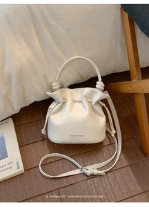 Detailed view of cream white leather bucket bag with drawstring closure and handle