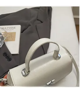 Détail du sac cylindre blanc montrant le simili cuir texturé et les boucles argentées