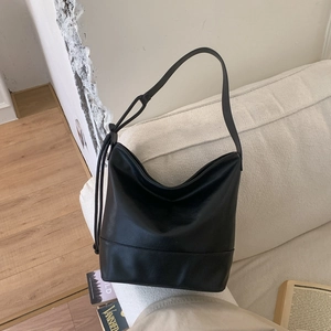 Detail of a black matte leather hobo bag with a wide strap on a white sofa