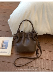 Detailed view of dark brown leather bucket bag with drawstring and brand logo
