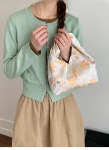 Detailansicht der cremefarbenen Blumen-Handtasche aus Satin mit Modell