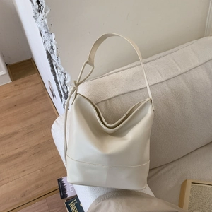 Detail view of cream PU leather hobo shoulder bag with soft texture on fabric sofa