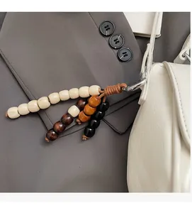 Gros plan détaillé du pendentif en perles de bois colorées sur un sac baguette blanc