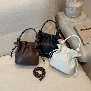 Three-color bucket bags in brown, black, and white with drawstring and brand logo