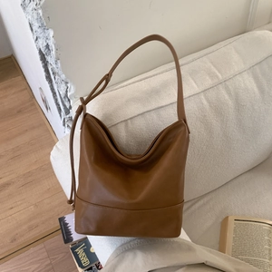 Detailed view of the soft caramel brown leather texture and side drawstring of the bag