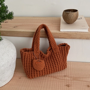 Détail du sac cabas tricoté main couleur caramel avec breloque cœur et texture tissée