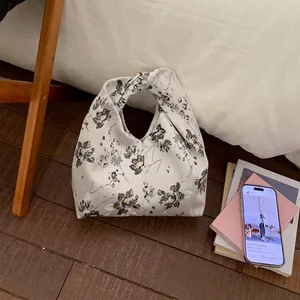 Detail der Satin-Knotenhandtasche in Perlengrau mit kunstvollen Blumenmustern