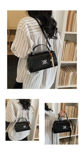 Détail du sac bandoulière noir texturé avec boucle X argentée et pompon perlé coloré