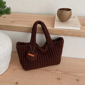 Détail d'un sac à main tricoté marron foncé avec texture tissée et étiquette coeur