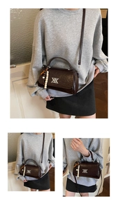 Gros plan du sac bandoulière en cuir marron foncé avec breloque perlée et logo argent