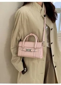 Borsa rosa effetto coccodrillo con chiusura in metallo indossata con un trench