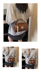 Détail du sac en cuir marron vintage avec logo métallique et pendentif pompon perlé