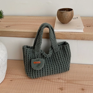 Gros plan détaillé du sac en tricot gris foncé avec étiquette en cuir Hand Made