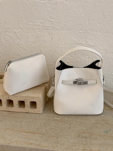 Cream white leather bucket bag set with silver hardware on a textured stone background