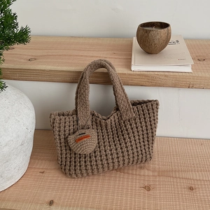 Détail d'un sac à main marron tricoté à la main avec motif gaufré et pendentif cœur