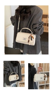 Détail du sac à main en cuir beige avec logo XK et pompon décoratif en perles de bois