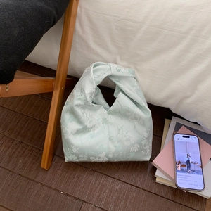 Detailansicht der minzgrünen Handtasche mit Knotengriff und weißem Jacquard-Blumenmuster